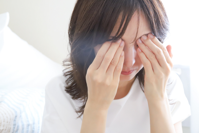 頭痛で目を押さえている女性