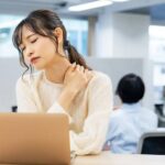 片側の肩こりを感じて肩を押さえる女性